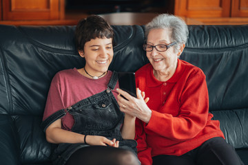 Wall Mural - Granddaughter teaches her grandmother how to use a mobile phone