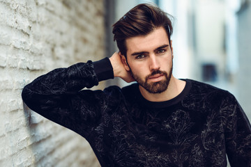 Young bearded man, model of fashion, in urban background wearing casual clothes.