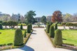 The statue of Jacinto Beravente is in the middle of the paths that cross in the Parterre Gardens (Spanish: Jardín del Parterre) of Madrid, Spain with trimmed trees and colourful flowers on either side