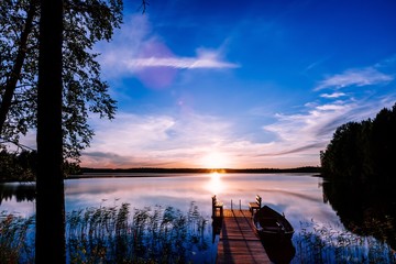 Wooden pier with fishing boat at sunset on a lake in Finland