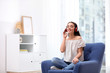 © New Africa - Young woman with headphones resting in armchair at home