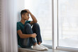 © New Africa - Upset African-American teenage boy sitting alone near window