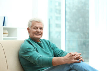 Wall Mural - Portrait of handsome mature man on sofa indoors