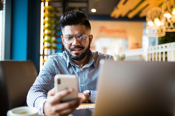 closeup shot of a young indian man typing a text on mobile phone. guy holding a modern smartphone an