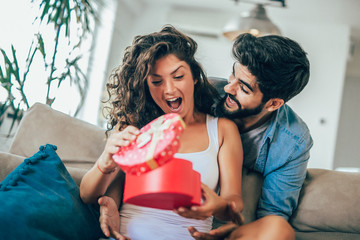 Wall Mural - Man giving a surprise gift to woman at home