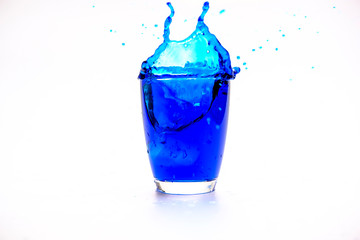 Blue water splashing in glass on white background