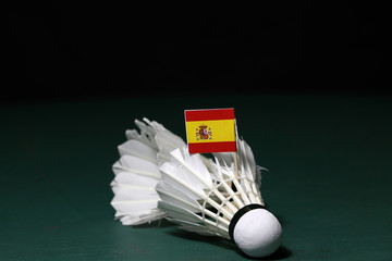 Mini Spain flag stick on the used shuttlecocks on green floor of Badminton court.