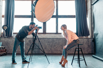 Wall Mural - stylish girl bending to the photographer in the room, side view photo