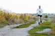 Middle age man running alone outdoors countryside at fall
