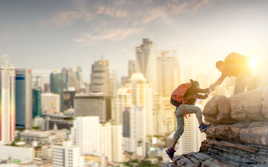 Wall Mural - asia couple hiking help each other in mountains with sunlight and city background.