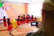 Woman taking video of children's morning party. Children on matinee at kindergarten