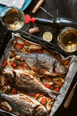 dinner concept for two. two glasses of white wine, baked fish.