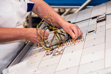 Wall Mural - Hands of an employee who tests a part of the wiring for cars at a modern plant at a special stand in the production shop