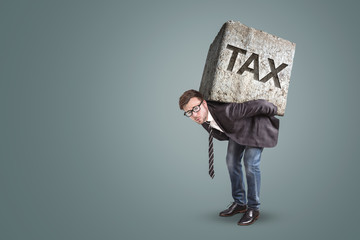 businessman carrying a heavy stone with the word tax on it