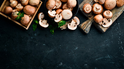 Mushrooms on a black stone background. Champignons Top view. Free copy space.