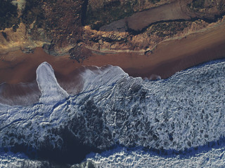 Aerial view of sandy beach with waves and clear ocean water. Drone photo