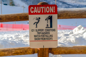 Caution sign on wooden fence against snow