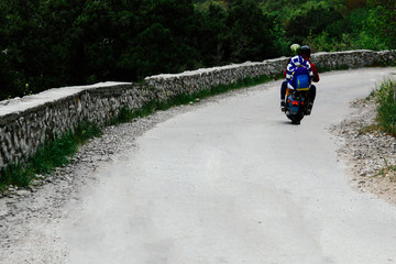 Two people riding a mountain road on a vintage scooter. Conceptually for travelers and lovers of vintage scooters