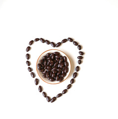 Nuts arranged in heart shape on background. Food image close up candy, chocolate milk, extra dark almond nuts. Love Texture on white grey table top view