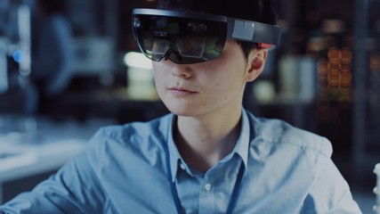 Leinwandbilder - Professional Japanese Electronics Development Engineer in Blue Shirt is Wearing a Virtual Reality Headset and Looking Around the High Tech Research Laboratory with Modern Computer Equipment.