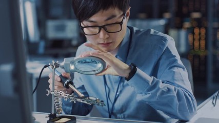 Leinwandbilder - Close Up of a Professional Japanese Electronics Development Engineer in Blue Shirt Soldering a Circuit Board in a High Tech Research Laboratory with Modern Computer Equipment