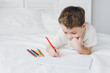 © irina_timokhina - Boy draws with colorful pencils sitting on the bed