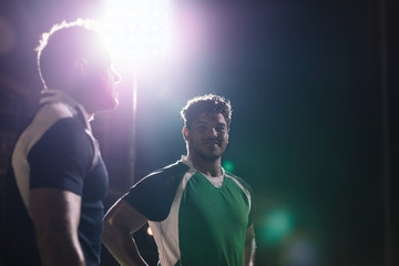 Wall Mural - Sportsmen standing on rugby field under lights