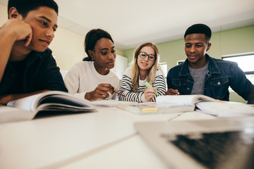 Students studying with books in classroom