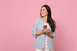 Smiling young woman in striped jacket looking aside using mobile phone, typing sms message isolated on pink pastel background in studio. People sincere emotions, lifestyle concept. Mock up copy space.