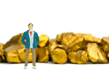 Figure miniature businessman or small people with pile of gold nuggets or gold ore on white background, precious stone or lump of golden stone, financial and business concept.