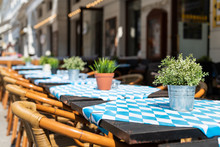 Closeup Of Empty Blue Tables Outside Restaurant Cafe Chair On Sidewalk Street Green Potted Flowers Plants Flowerpot Potted Setting Nobody