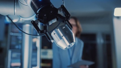 Poster - Close Up of a Futuristic Robotic Arm Moving a Metal Detail. Team of Engineers Observe This Technologically Advanced Process. They are in a High Tech Research Laboratory with Modern Equipment.