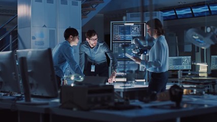 Poster - Diverse Team of Engineers with Laptop and a Tablet Analyse and Discuss How a Futuristic Robotic Arm Works and Moves a Metal Object. They are in a High Tech Research Laboratory with Modern Equipment.