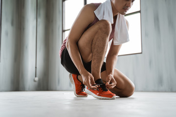 man sport tie his shoes before workout in the gym