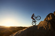 © anatoliy_gleb - Silhouette of courageous cyclist balancing on back wheel on trial bicycle. Professional sportsman biker making acrobatic stunt on the top of mountain at sunset. Concept of extreme sport. Copy space