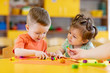 © Oksana Kuzmina - Kids boy and girl play in kindergarten with interest. Children sculpt from plasticine in day care centre.