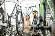 © rh2010 - Salesman helping young woman to choose a new bicycle to buy standing in the bicycle shop