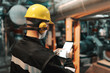 © dusanpetkovic1 - Caucasian worker in heavy industry plant with helmet and in uniform using tablet for work.
