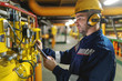 © dusanpetkovic1 - Profile of hardworking worker with helmet, antifones and in protective suit checking air pressure on boilers while standing in heavy industry plant