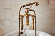 Water running down from antique bronze faucet tap into the bathtube. Indoors, stylish interior, copy space.