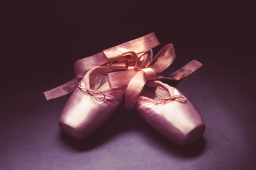 Wall Mural - Pointe shoes ballet dance shoes with a bow of ribbons beautifully folded on a dark background.