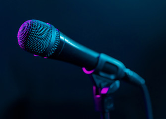 Microphone on black background with colorful pink and turquoise light. Music, concert concept.