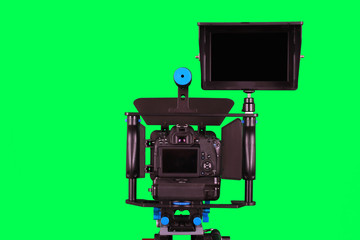  Dslr camera with additional screen for video shooting on the tripod, isolated on green background. The chromakey. Green screen.