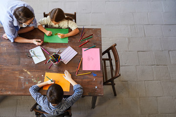 top view portrait of children painting pictures at table with mom, copy space