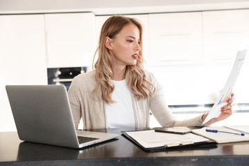 Poster - Blonde woman posing indoors at home using laptop computer work with documents.