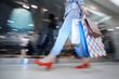 Blurred motion of lady shopaholic with paper bags in corridor of mall, unknown woman walking by shop-window