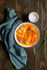 Wall Mural - Spring vegetable soup with chicken stock for one person on wooden table.  Rustic style, top view.