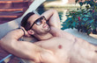 Handsome, muscular man relaxing by the swimming pool