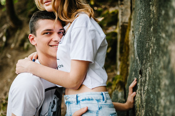 A woman's hands hug men on background large stone wall, rock. A young, stylish, love couple, upper length. Close up. Nature autumn. Side view.