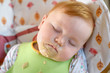 mit brei verschmiertes baby schläft nach essen im hochstuhl
